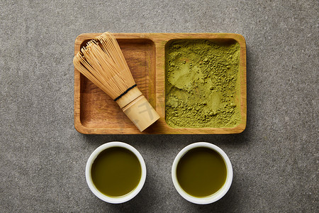 在木碗上用绿茶接近白杯的竹胡须和火柴粉的顶视图