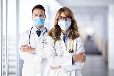 拍的女医生和男医生站在一起看着相机。医疗小组。医生戴口罩预防疾病.
