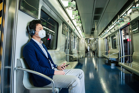 手机听音乐摄影照片_青年男子戴口罩乘坐地铁
