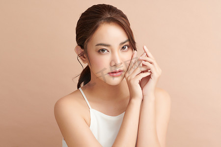肌肤补足水摄影照片_美丽的年轻亚洲女人，有着米色背景、面部护理、面部治疗、美容、美容美发、水疗、亚洲女性肖像等洁白新鲜的肌肤.