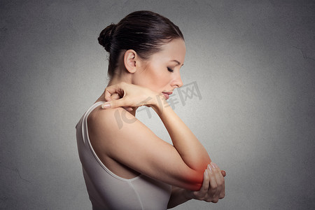 痛苦的手肘撑在灰色的背景上的女人 