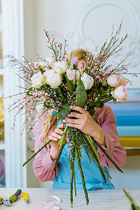 在花店, 女性花店拿着花束与白玫瑰在前面的脸 