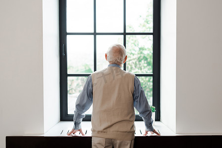 隔离期间站在窗边的孤独老人的背影