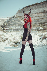 魔鬼鱼纹摄影照片_红色的头发和魔鬼角的女人