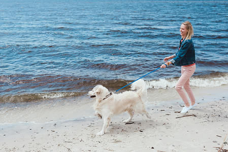 在海边遛狗的迷人的快乐女人