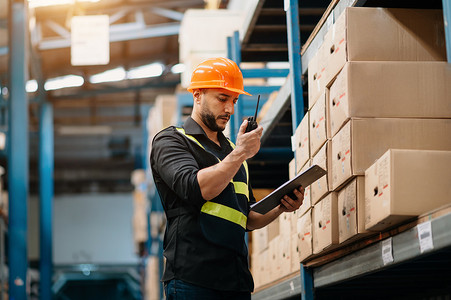 Storage worker in uniform and notepad,digital tablet in hands checks production.