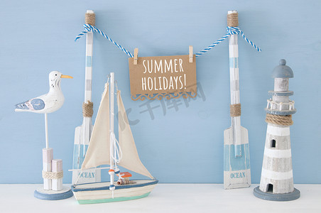海鸥装饰摄影照片_航海概念与木制装饰船桨和悬挂注意信息在一个字符串旁边的灯塔, 海鸥和船超过蓝色背景.