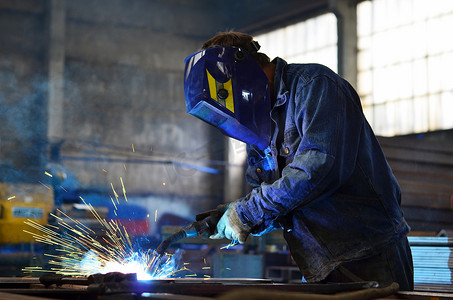 电焊工人摄影照片_在工厂制造金属的焊机