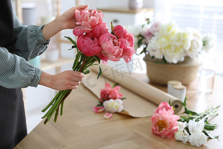 花匠在餐桌旁做着美丽的牡丹花束，特写