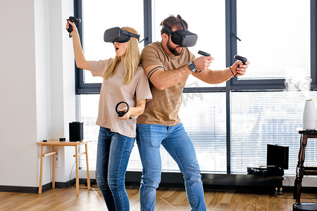 快乐的高加索夫妇使用VR头盔与控制者在电子游戏中玩耍