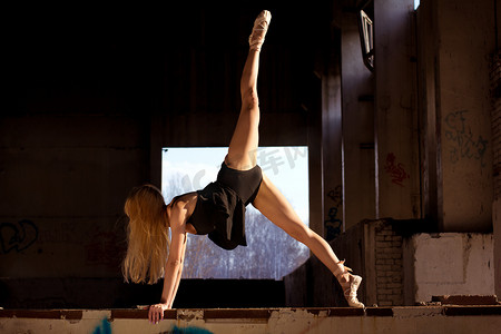 绝对让人叹为观止的性能。芭蕾舞女演员在黑暗的废弃厂房在阳光下舞蹈.