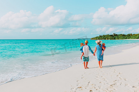 两个小孩的家庭在热带海滩上行走