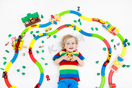 孩子们玩玩具火车铁路.孩子们在玩彩色彩虹木火车.给小男孩的玩具学龄前儿童在家里或托儿所、幼儿园建造铁路。幼儿园教育游戏.