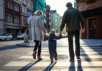 城市里有父母横穿马路的幼儿男孩的后视镜.