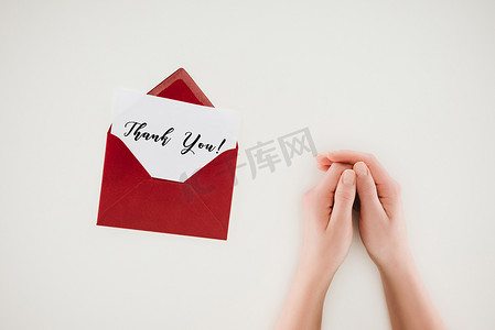 裁剪拍摄的女人手牵着手附近打开红色信封与感谢你在纸上孤立的文字在白色