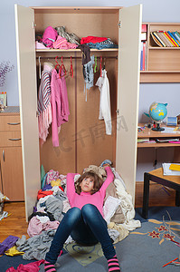 凌乱的衣柜摄影照片_凌乱的十几岁女孩躺在堆皱衣服里面她的衣柜