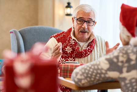 白发老人戴着眼镜和妻子坐在小餐桌旁, 在家里享受圣诞假期, 复印空间