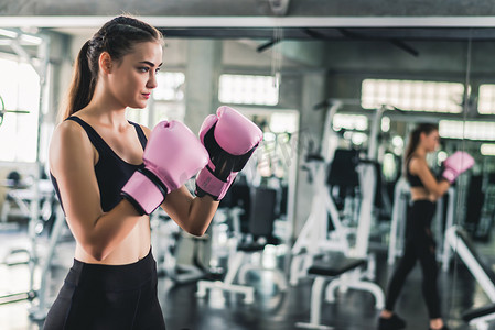 在健身房锻炼时，戴着粉色拳击手套的白种女人非常迷人. 