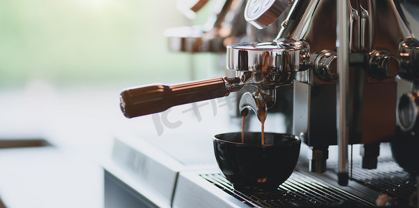 入杯摄影照片_咖啡从浓缩咖啡机倒入咖啡店咖啡杯的特写镜头 