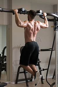 男子运动员做拉 Ups-引体向上在健身房里