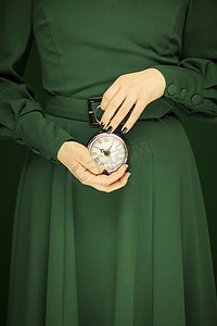 美丽的女人身材绿色的衣服与绿色背景举行复古钟, 色调绿色
