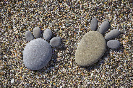 两个跟踪脚石头做成的卵石的海滩背景幕布上