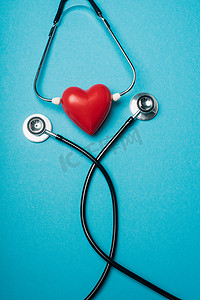 蓝色背景的黑色听诊器装饰红心的顶视图，世界卫生日的概念