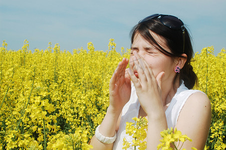 年轻女子因为花粉过敏而在花丛中打喷嚏