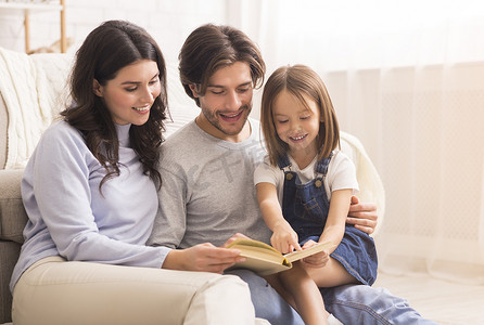 little摄影照片_Parents teaching their little daughter how to read at home