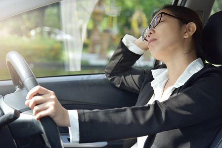 疲惫开车摄影照片_开车时睡着的女商人.