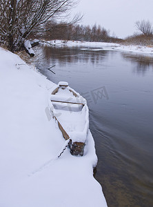 河岸摄影照片_冬天河岸边覆盖着雪的木船