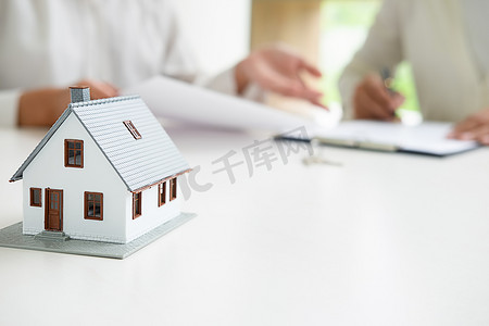 贷款摄影照片_与房地产经纪人和客户讨论购房、保险或贷款房地产背景的房模.