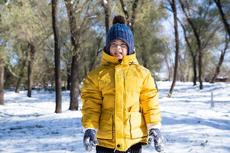 雪地里玩耍摄影照片_快乐的小男孩在雪地里玩耍