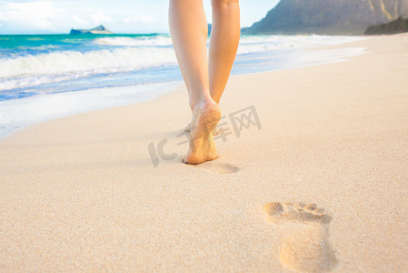 在沙滩上行走的女人在沙滩上留下脚印.