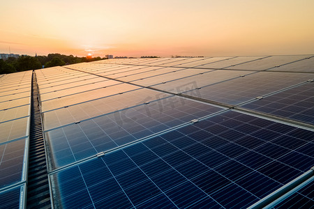 蓝色光电太阳能电池板安装在建筑物的屋顶上，以便在日落时产生清洁的生态电力。可再生能源概念的生产