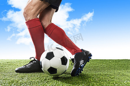 足球红蓝摄影照片_球员的腿在红色袜子和黑色鞋子运行和运球与球在户外玩