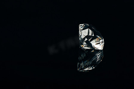 纯黑色摄影照片_透明纯钻石隔离在黑色与反射