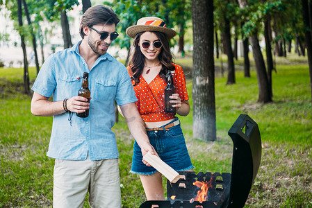 驴皮火烧摄影照片_微笑夫妇在太阳镜与啤酒一起放火烧烧烤
