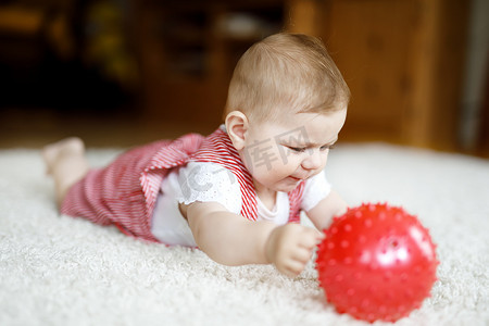 可爱的宝宝玩红胶球。小女孩看着相机和爬行。家庭，新的生活，童年，开始概念。宝宝学习抓斗.