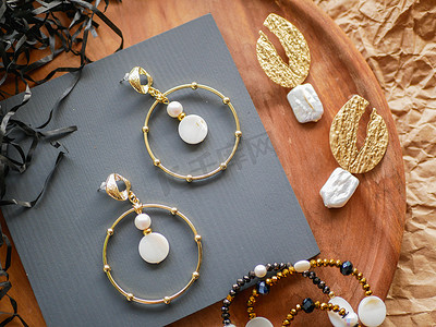金耳环。 女人的珠宝 复古装饰背景。 木制托盘上漂亮的金色胸针、手镯、项链和耳环。 平躺在地上，俯瞰四周