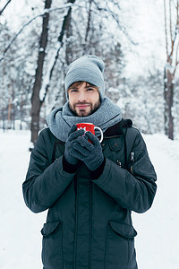 冬天公园手捧着一杯热咖啡的年轻人