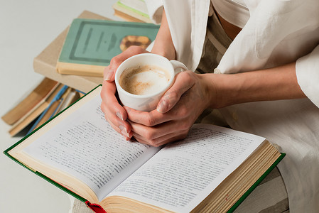 带着书架的女人的剪影，手里拿着一杯被白色隔离的咖啡 
