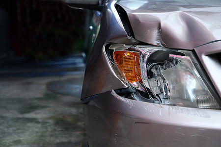 金黄色汽车的前灯坏了.破碎的汽车毁坏了汽车的零件.车祸保险很重要