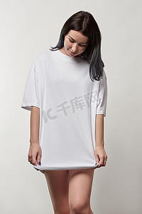 美丽的年轻女子在白色超大 t恤与复制空间隔离在灰色