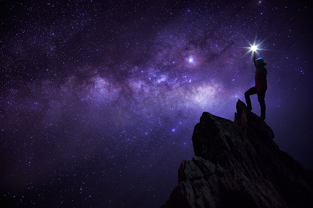 宇宙岩石摄影照片_登山者或背包客的剪影, 他把明星高高举起头顶。站在岩石山峰上对抗银河系, 恒星和太空尘埃在宇宙中, 成功, 领导概念.