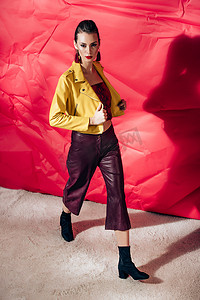 时尚模特摆在黄色皮夹克红色背景上的时尚拍摄