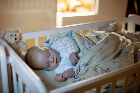 可爱的初生男婴，晚上睡在婴儿床