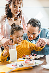 愉快的家庭一起吃薄饼与莓果在桌在厨房