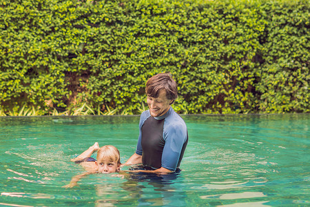 教游泳摄影照片_男教师游泳为孩子教一个快乐的男孩游泳在水池里.