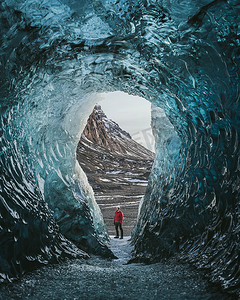 Traveler with a backpack in an ice cave. Man standing on the glacier Vatnajokull in Iceland. Epic landscape in Iceland. Travel and adventure concept.